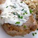 Pork Chops with cream cheese sauce on a white plate with quinoa